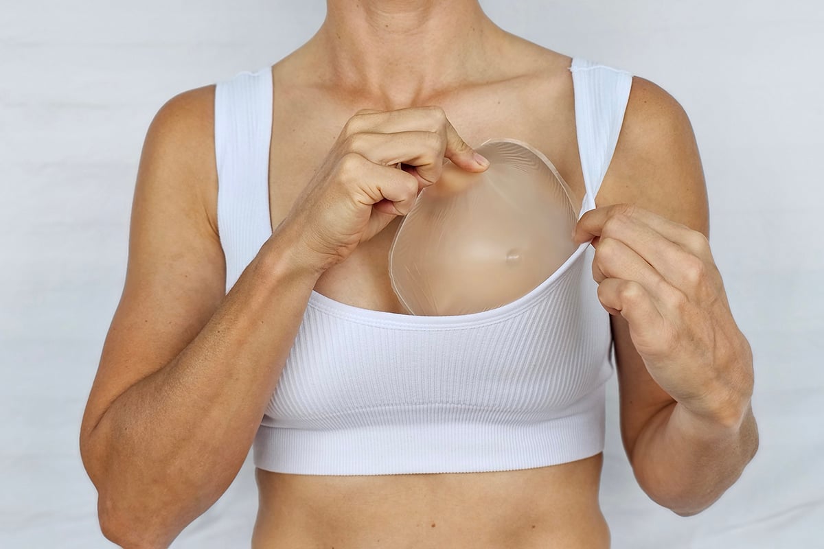 a woman demonstrates the process of breast augmentation using a silicone implant
